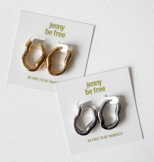 The Organic Hoop earrings by Jenny Be Free in gold and silver finish are shown against on branded packaging.