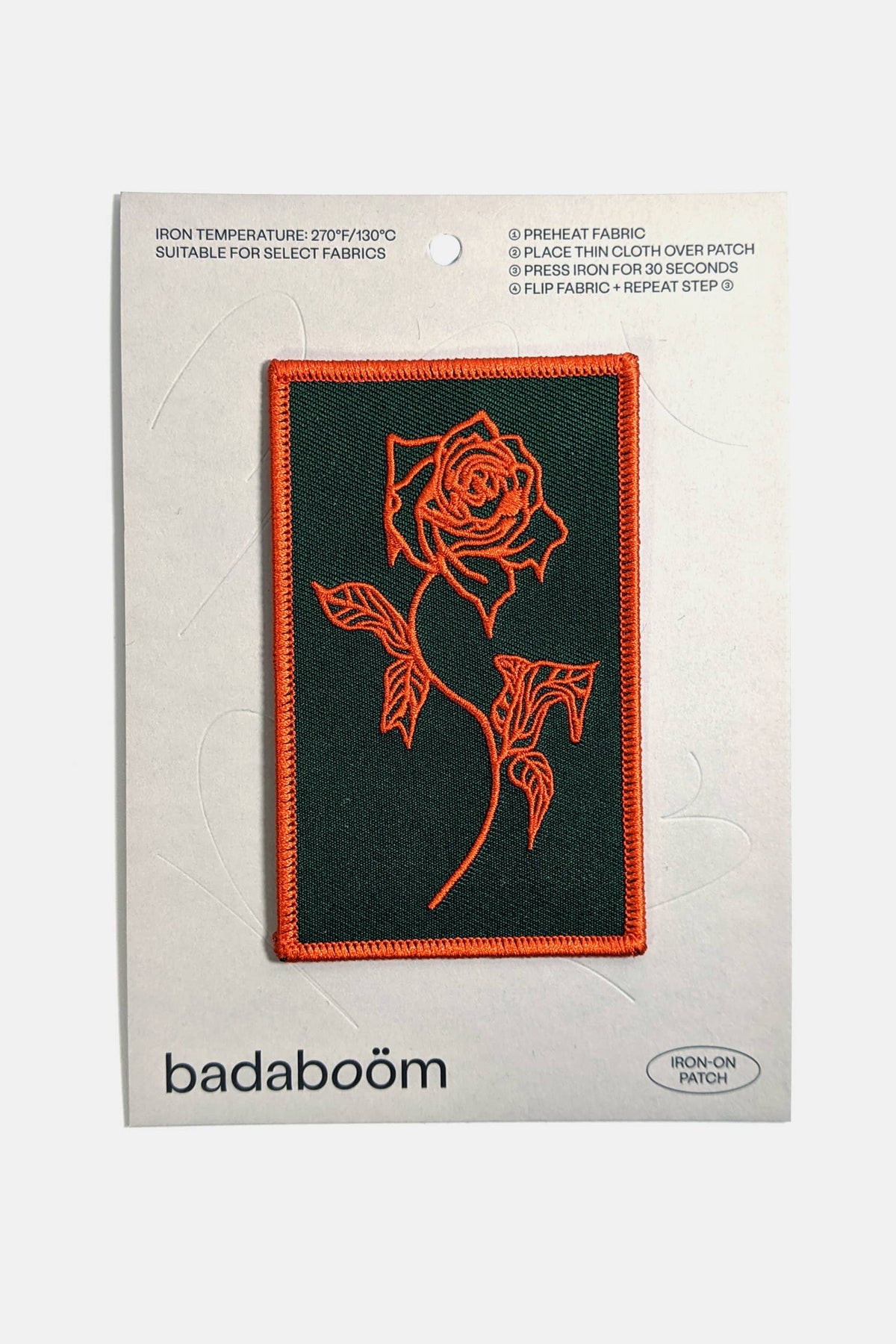 An embroidered rectangular patch from Badaboöm Studio, featuring a red Rose design on a black background, shown on a card against a white background.