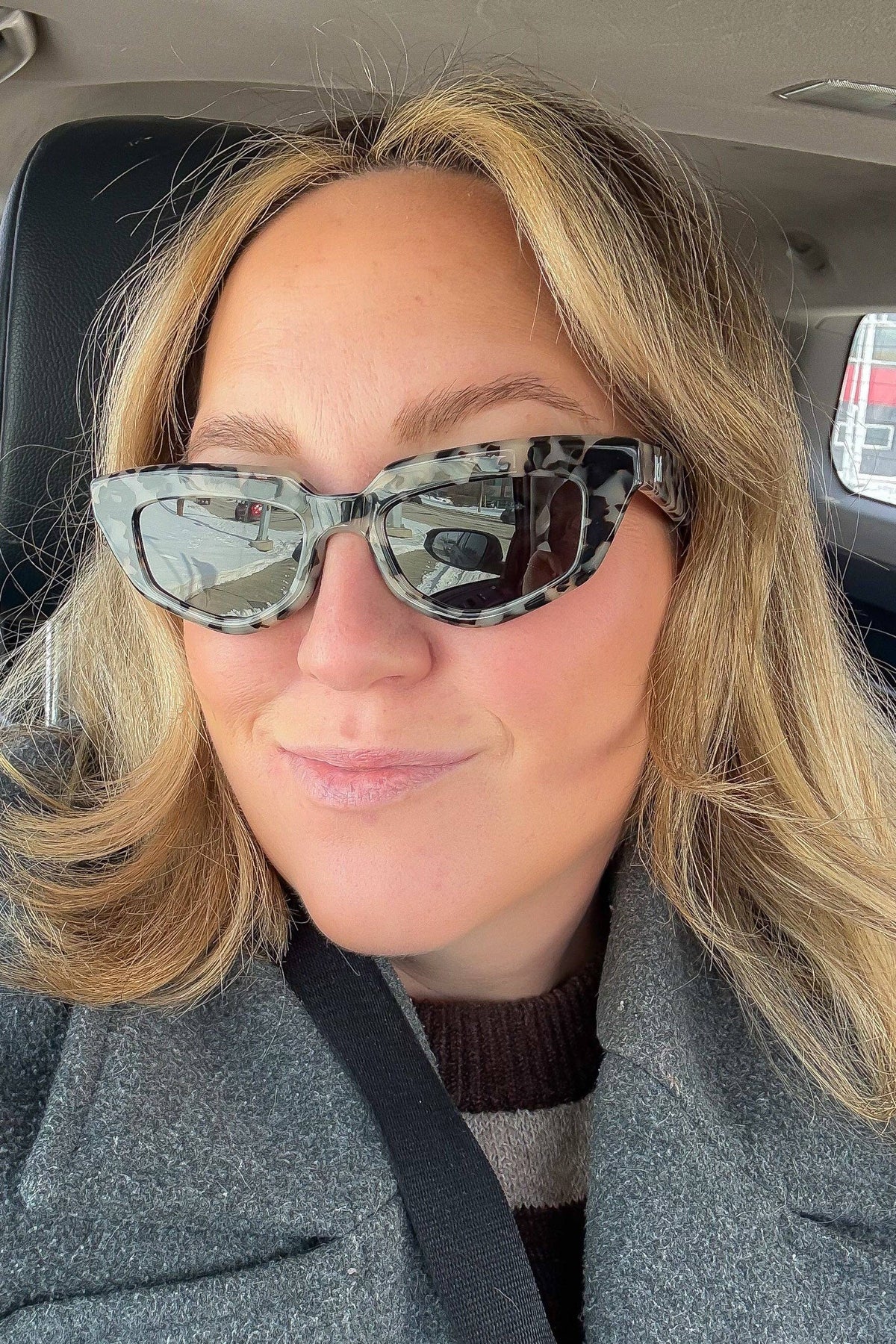A woman wearing the Vintage Tortoise Sunglasses by Jenny Be Free, sitting in a car.