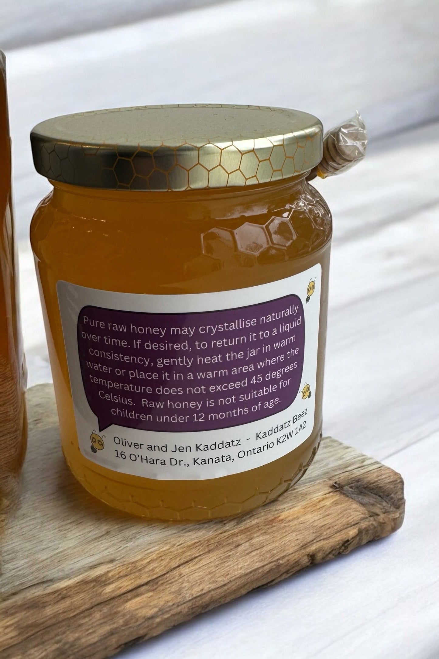 A jar of Daytripper Honey by Kaddatz is shown on a wooden cutting board in front of a tiled wall.