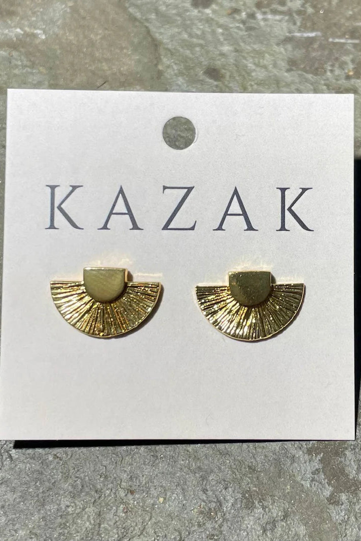 Brass fan-shaped earrings on a 'KAZAK' branded card against a stone background