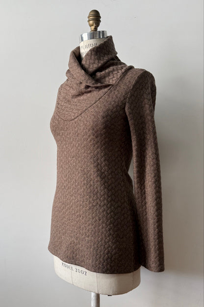 A side view of the Eloi Sweater by Kollontai in Brown, a slim fitting textured sweater with a large crossover collar, is shown on a mannequin against a white background.