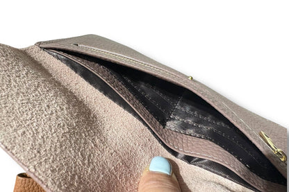 Close-up of a taupe textured leather  wallet from Armoir being opened to show a black interior pocket, with a finger pointing inside.
