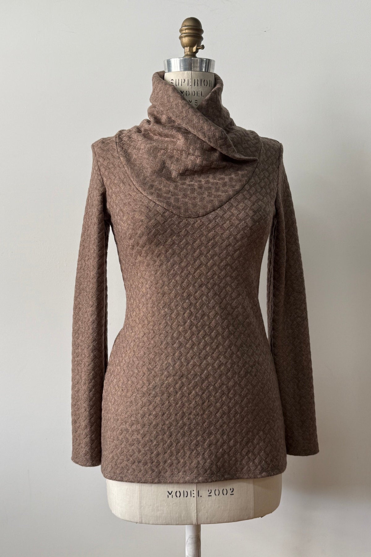 The Eloi Sweater by Kollontai in Brown, a slim fitting textured sweater with a large crossover collar, is shown on a mannequin against a white background. 