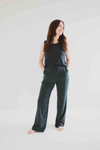 A woman wearing the Riviera Tank by Ang Hill in Juniper, a loose fitting tank with a round neck and white straps in cotton/modal. She is wearing it with matching pants and standing in front of a white background. 