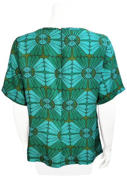 A back view of the Cecil Box Blouse by Mandala in Vintage Tile print is shown on a mannequin against a white background. It has a high neckline, wide 1/2 sleeves, and a side hem slit detail.