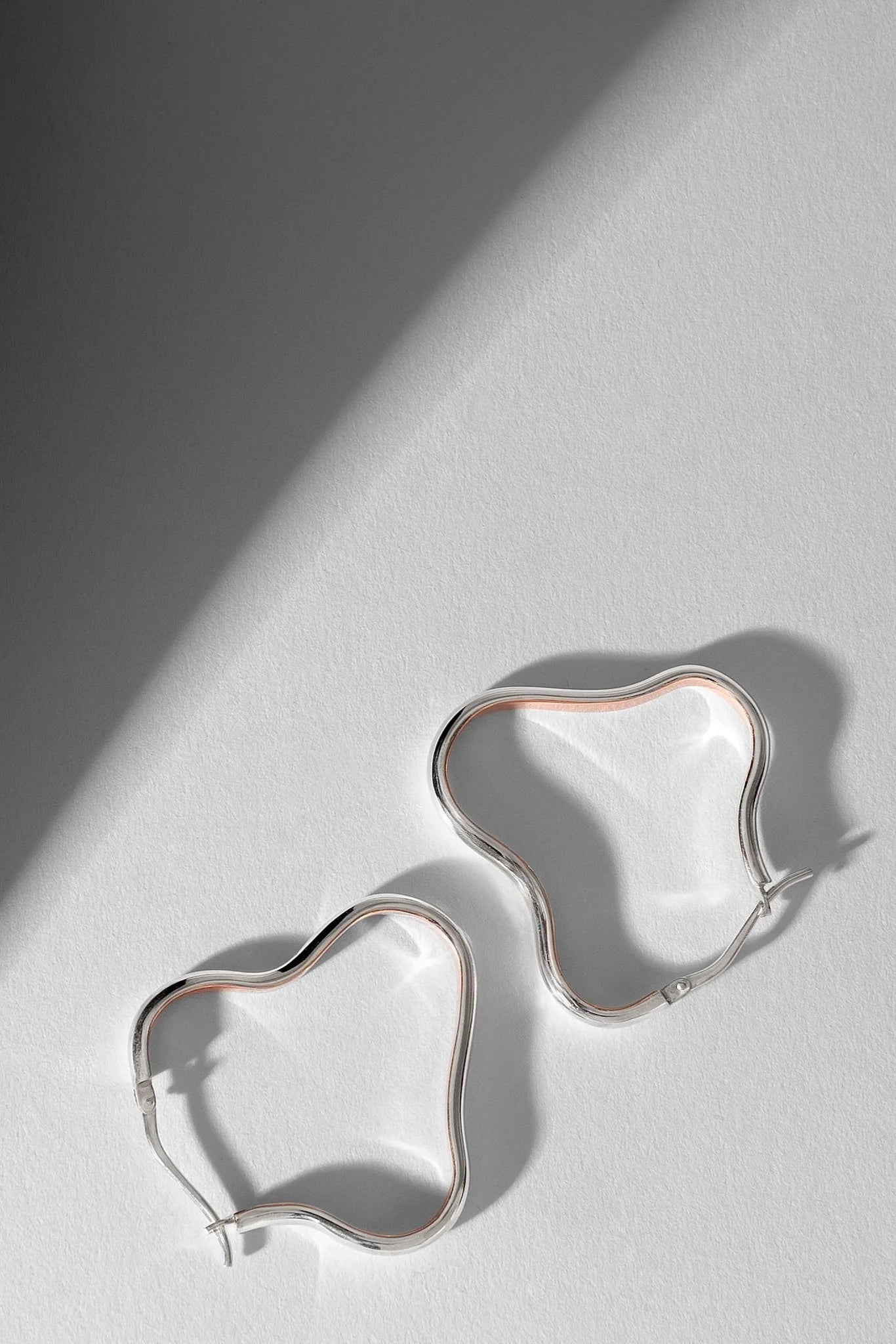 Silver earrings on a light gray surface with a soft shadow