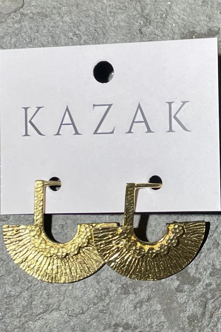 Brass earrings on a 'KAZAK' branded card against a grey background