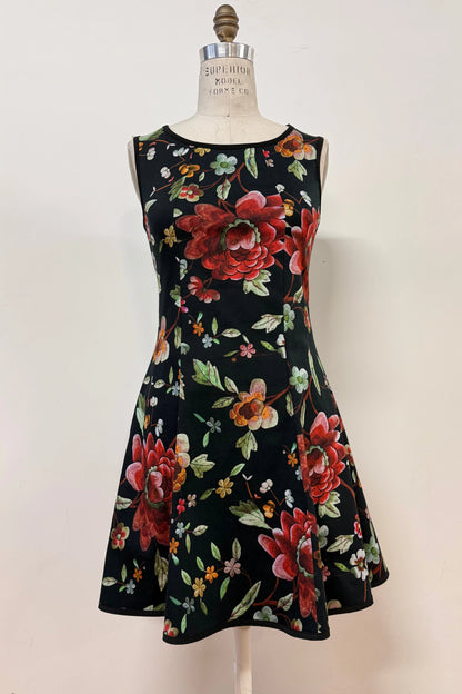 The Silba Dress FW26/27 by Kollontai in Black Floral, a short sleeveless dress with princess seams and an above the knee skirt, is shown on a mannequin against a white background. 