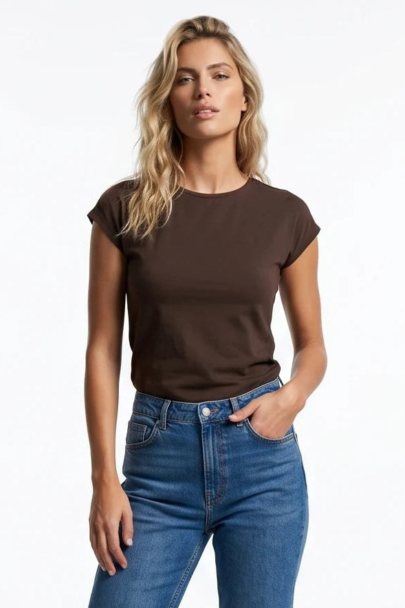A woman wearing the Eowyn T-Shirt by Kollontai in Chocolate with jeans standing against a grey background. 