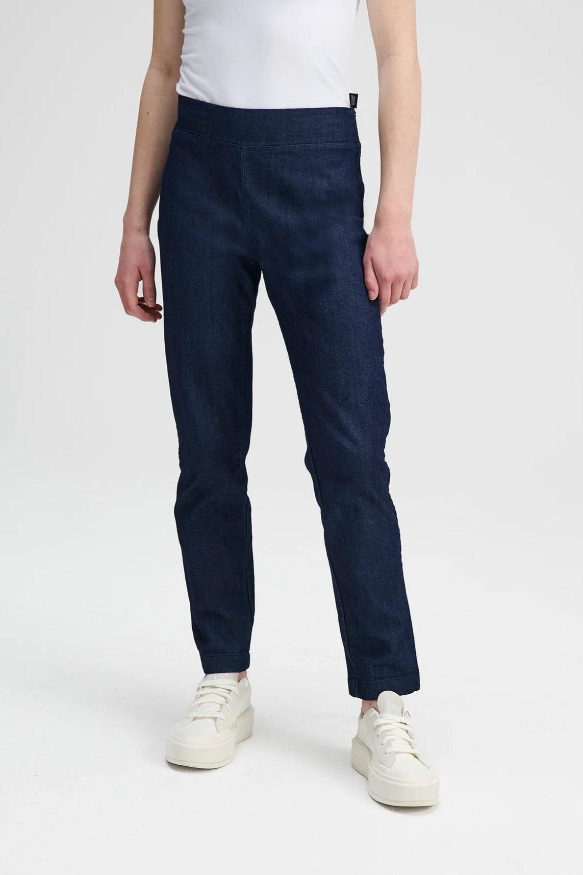 Waist down view of a woman wearing the Potton Denim Pants by Message Factory, slim fitting jeans with a side zipper, with a white t-shirt, on a white background