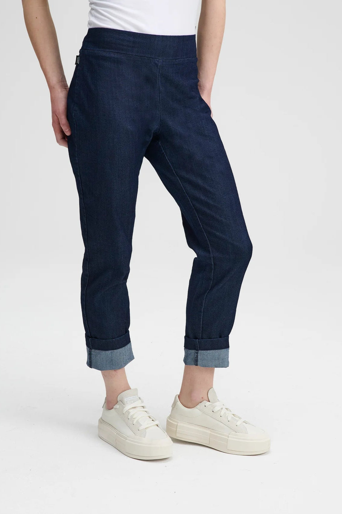  Waist down view of a woman wearing the Potton Denim Pants by Message Factory, slim fitting jeans with a side zipper, with a white t-shirt, on a white background