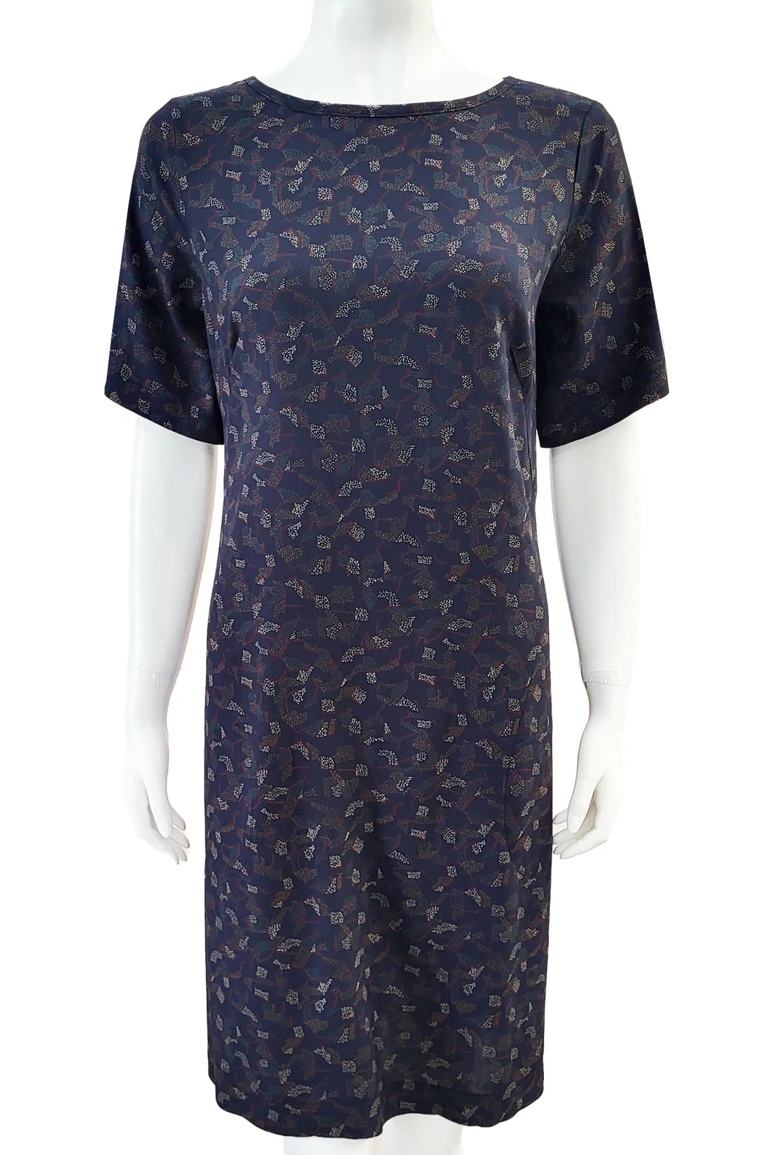 The Cecily Simple Shift Dress from Mandala in Night Hex print is shown on a mannequin against a white background. It has a high neck, short sleeves, a knee-length hem, French darts, and elastic at the back of the waist. 