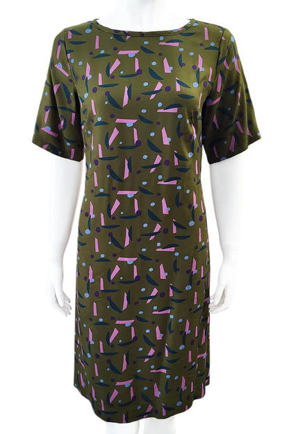 The Cecily Simple Shift Dress from Mandala in Playtime Ivy print is shown on a mannequin against a white background. It has a high neck, short sleeves, a knee-length hem, French darts, and elastic at the back of the waist. 