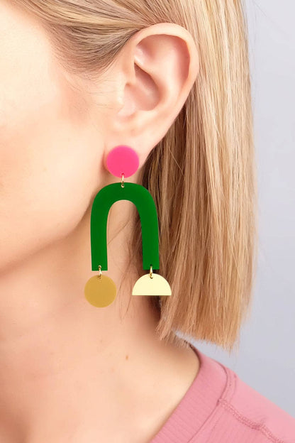 Earring with pink top, green middle, and gold bottom on a blurred background