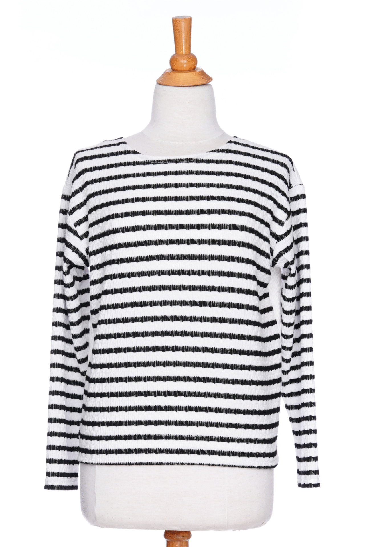 The Collins Reversible Sweater by Rien ne se Perd in Black/White is shown on a mannequin agains ta white background. t's reversible back to front with stripes on side and solid fabric on the other. It has long striped sleeves and a round neck. 