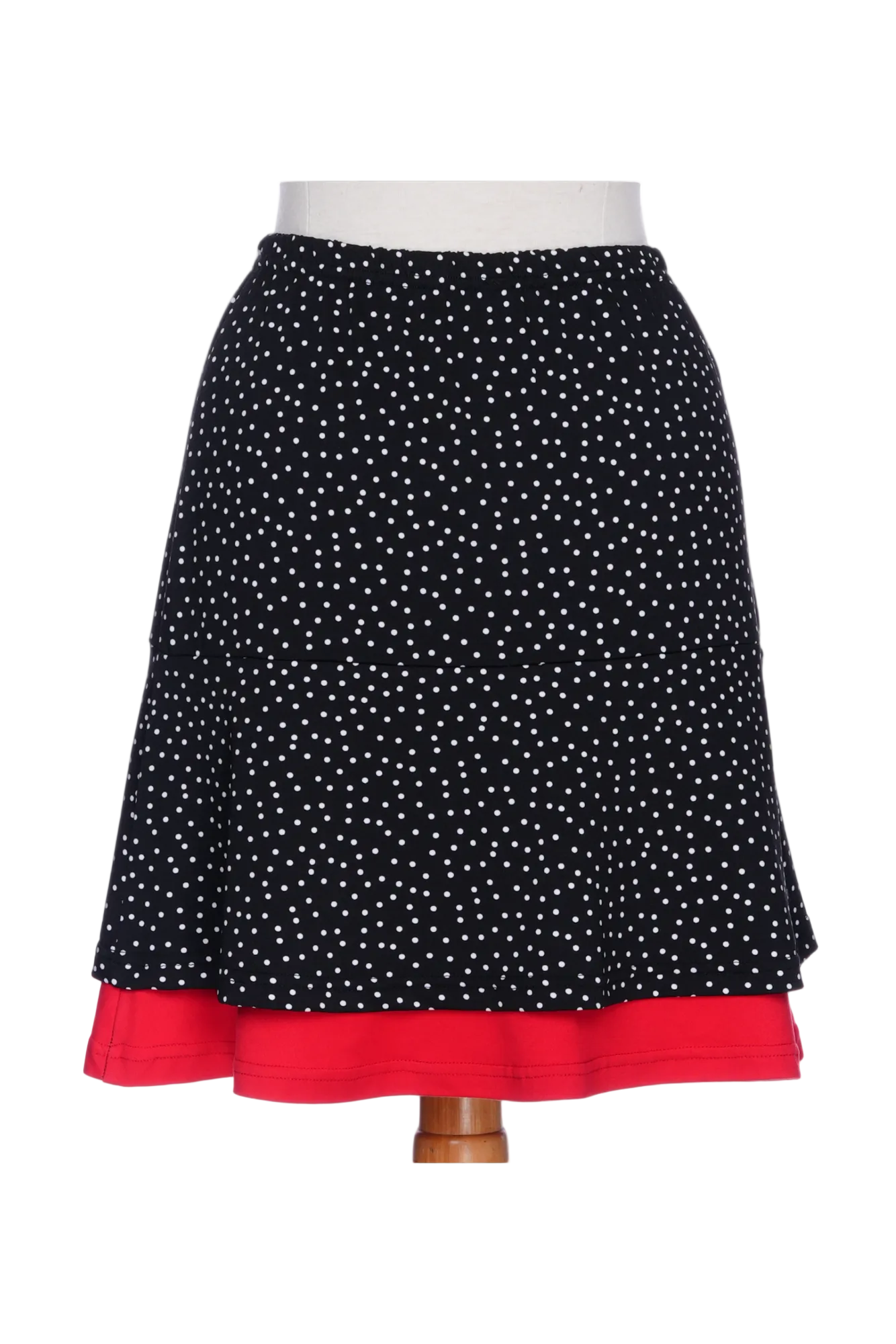 A back view the Sambuca Skirt from Rien ne se Perd in black and white polka dots with a Red peekaboo ruffle. It has an elastic waist and an A-line shape that hits above the knee. 