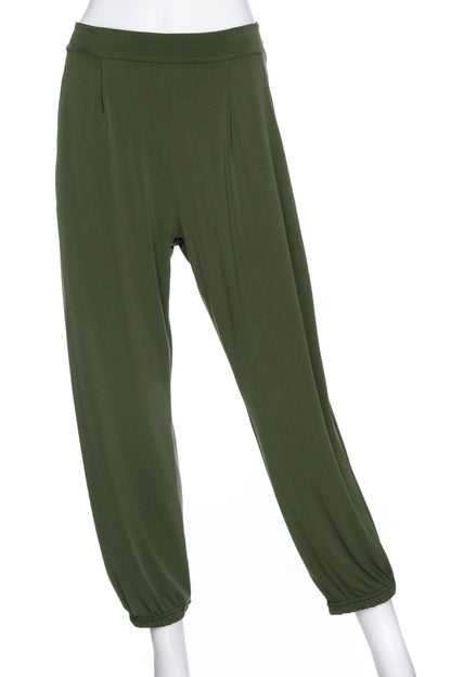The Pina 7/8 Pants by Rien ne se Perd in Olive, with a pull on waist, front pleats, cuffed legs, and a pockets, are shown on a mannequin in front of a white background. 