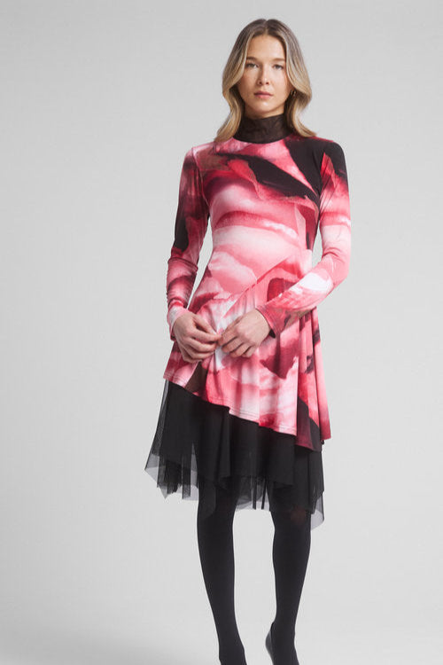 A woman wearing the Joe Tunic by Dinh Ba in Red, an asymmetrical tunic in a swirl pattern with a contrasting black mesh turtleneck and long sleeves. 