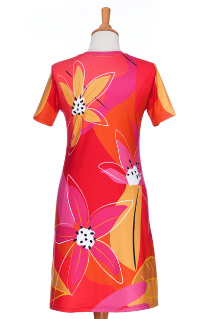 A back view of the Aperol Dress from Rien ne se Perd, a short flared dress with a V-neck, short sleeves, and a colourful Pink floral pattern, is shown on a mannequin in front of a white background. 