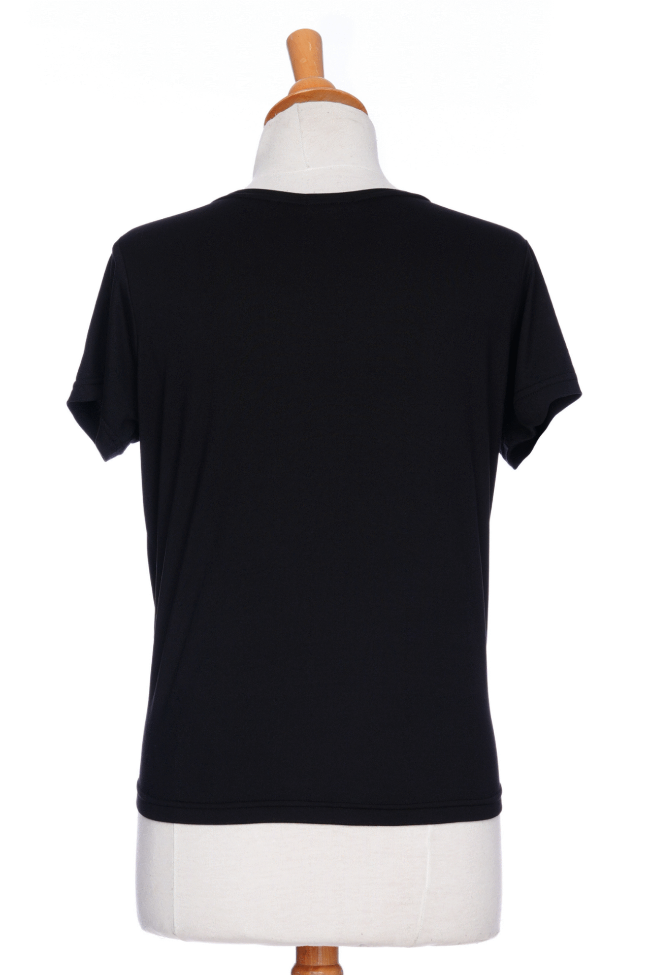 A back view of the Tropical T-shirt from Rien ne se Perd in black, with a wide neck, hi-low hemline, and tie detail at the front, is shown on a mannequin in front of a white background. 