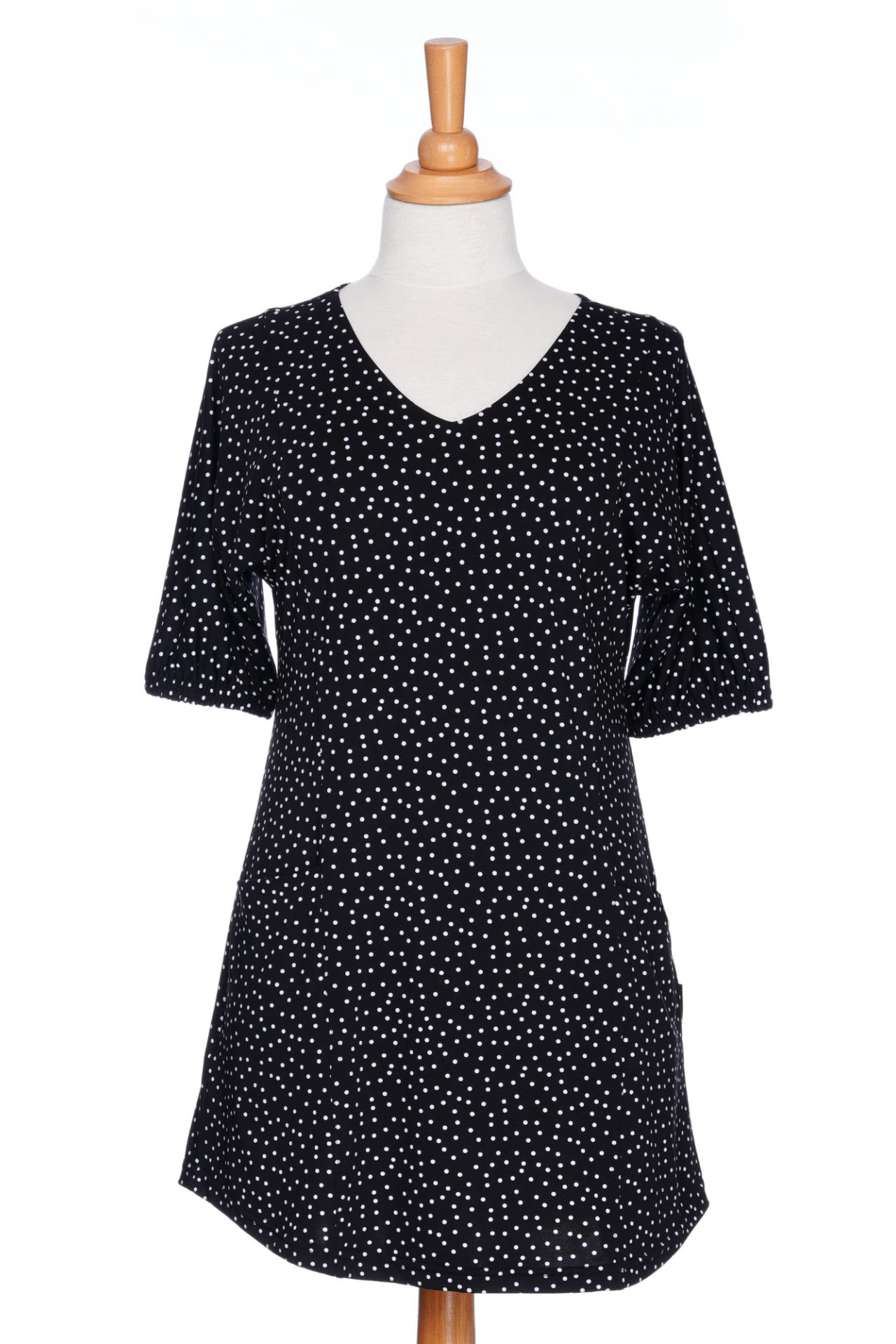 The Martini Tunic from Rien ne se Perd, a black polka dot piece with full elbow length sleeves with gathered cuffs, and two patch pockets., is shown on a mannequin against a white background. 