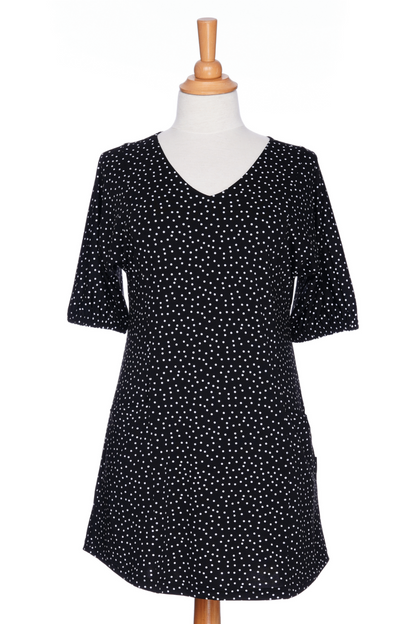 The Martini Tunic from Rien ne se Perd, a black polka dot piece with full elbow length sleeves with gathered cuffs, and two patch pockets., is shown on a mannequin against a white background. 
