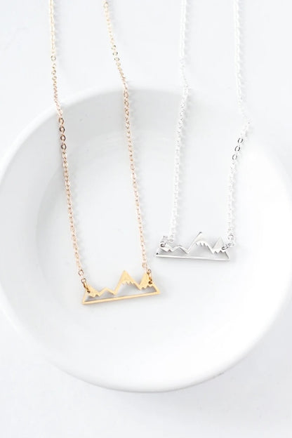 Mountain necklace by Birch Jewellery; silver and gold; flat lay styled on a white ceramic dish